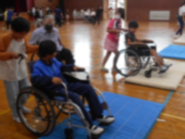 持ち上げ方に気を付けながら車いすを進める児童